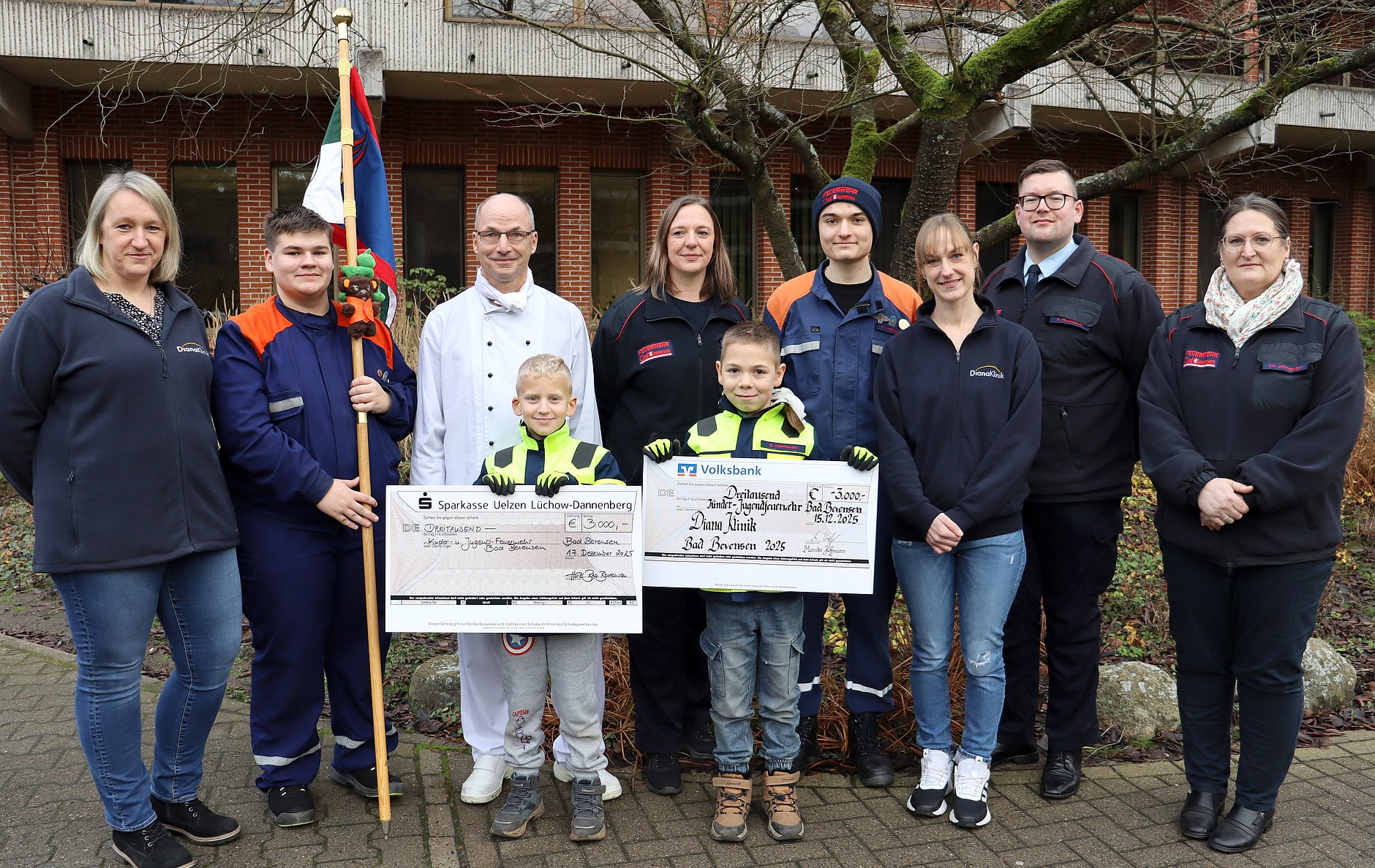 Feuerwehrleute und Klinik-Vertreter bei der Übergabe zwei symbolischer Schecks