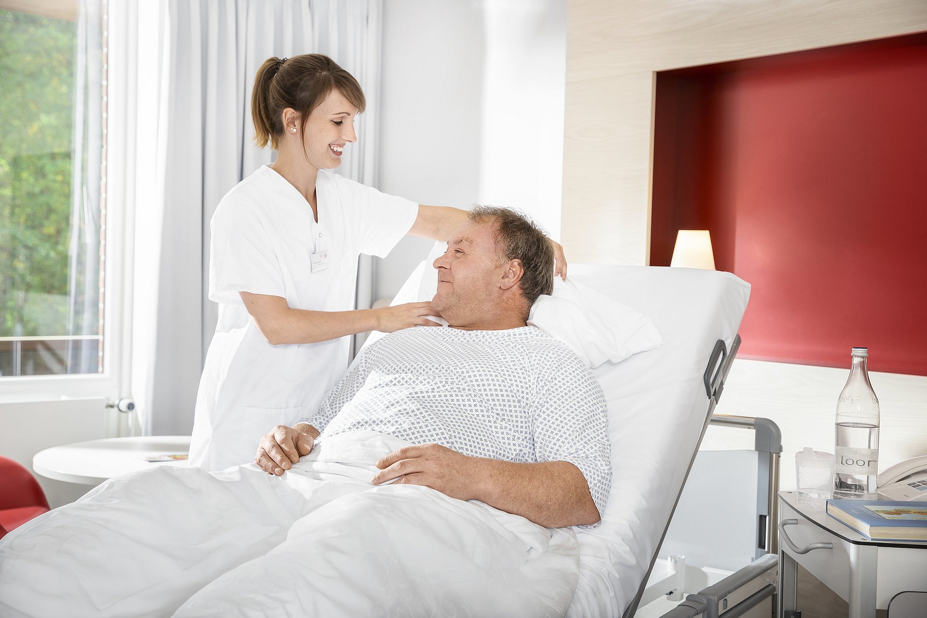 HGZ | Pflege im HGZ Dies ist ein Pflegerin am Bett eines Patientin im Patientenzimmer.
