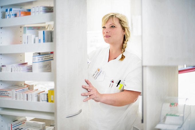 Dies ist eine Pflegekraft die etwas aus einem Medikamentenschrank heraussucht.