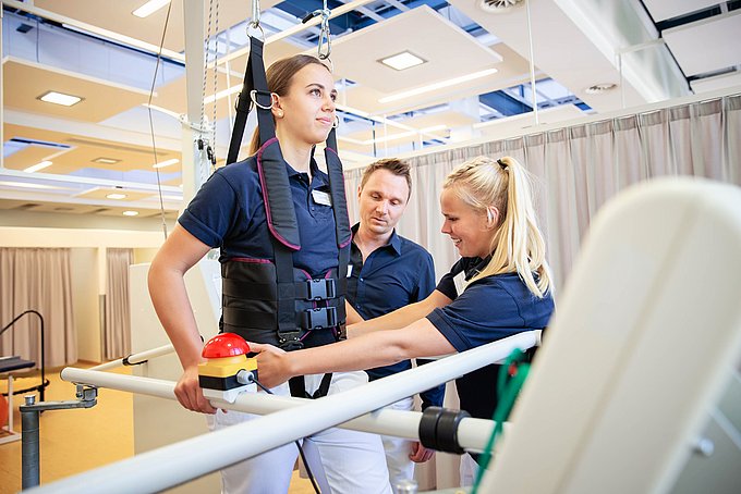 Dies sind eine zwei Schülerinnen und ihr Lehrer während einer praktischen Übung in der Physiotherapieschule der Diana Gruppe am HGZ.