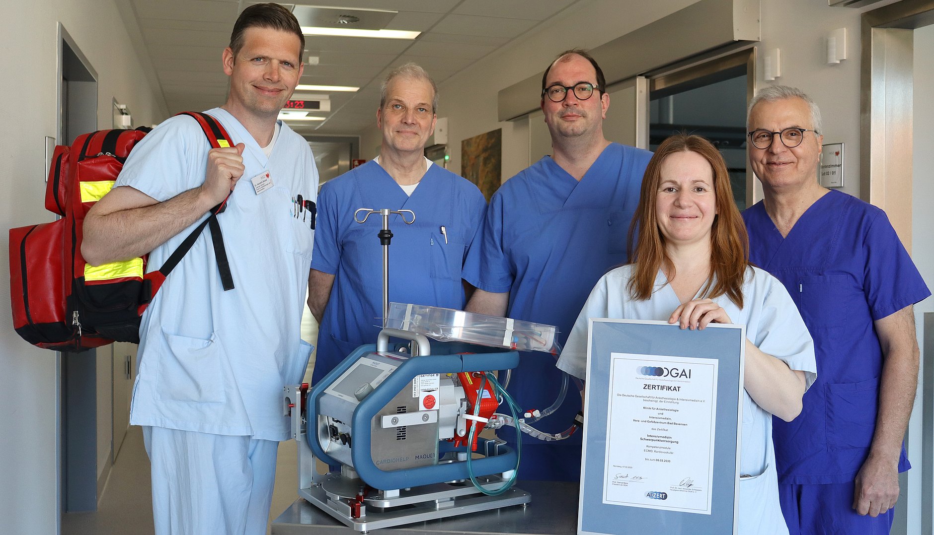 Fünf Personen präsentieren auf einer Intensivstation ein ECMO-Gerät sowie ein Zertifikat der Deutschen Gesellschaft für Anästhesiologie und Intensivmedizin.