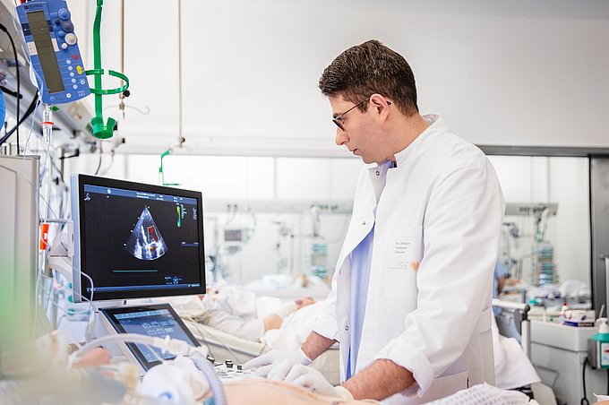 Dies zeigt einen Anästhesisten, der eine Echokardiografie bei einem Patienten auf der Intensivstation durchführt.