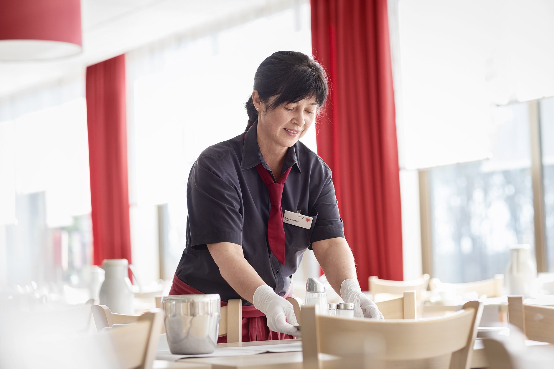 HGZ | Service Dies ist eine Servicekraft, die sorgfältig einen Tisch eindeckt.