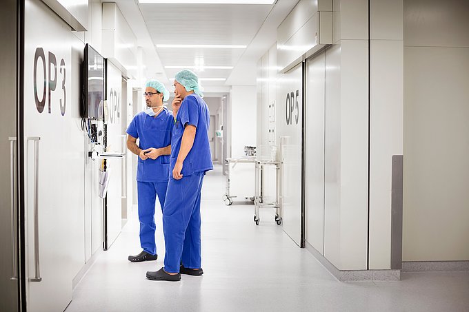 Dies sind zwei Ärzte, die sich im Flur des Operationstrakts miteinander beraten.