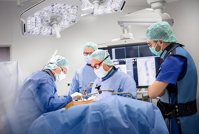 Dies zeigt Gefäßchirurgen bei einer Operation an der Aorta in einem Hybrid-OP.