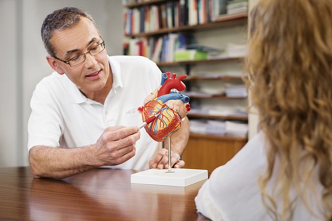 Dies ist ein Arzt, der etwas einer Patientin an einem Herzmodell erläutert.